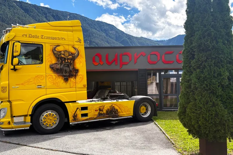 Gelb lackierte Sattelzugmaschine vor dem Betriebsgebäude von AUPROCA in Nassereith